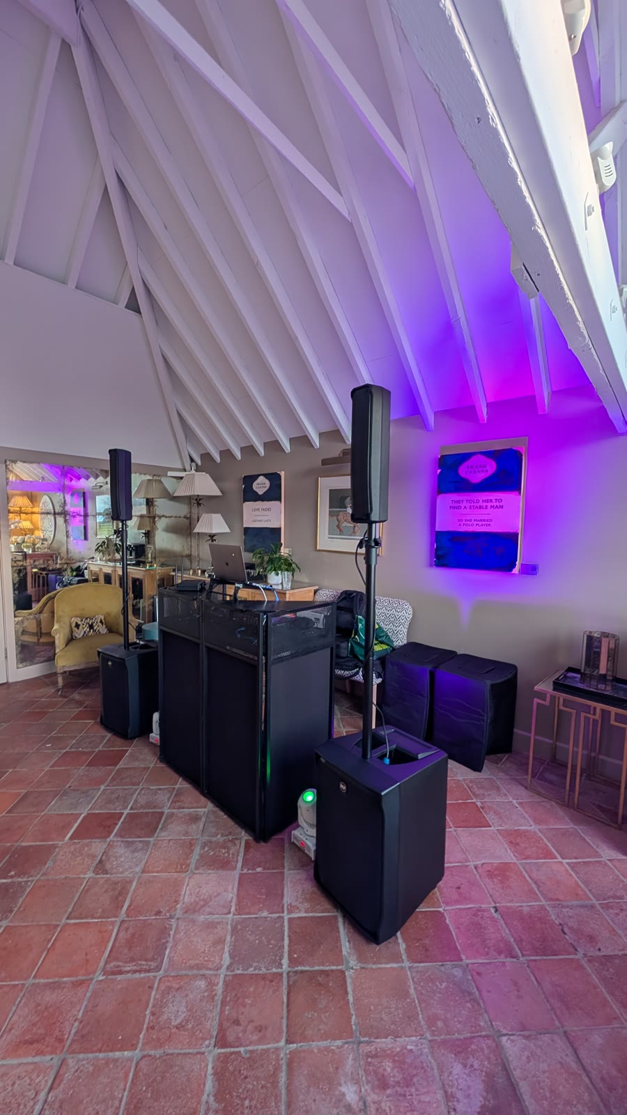 Compact DJ setup with two column speakers and a black booth in a vaulted room